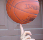 a hand spinning a basketball atop one finger